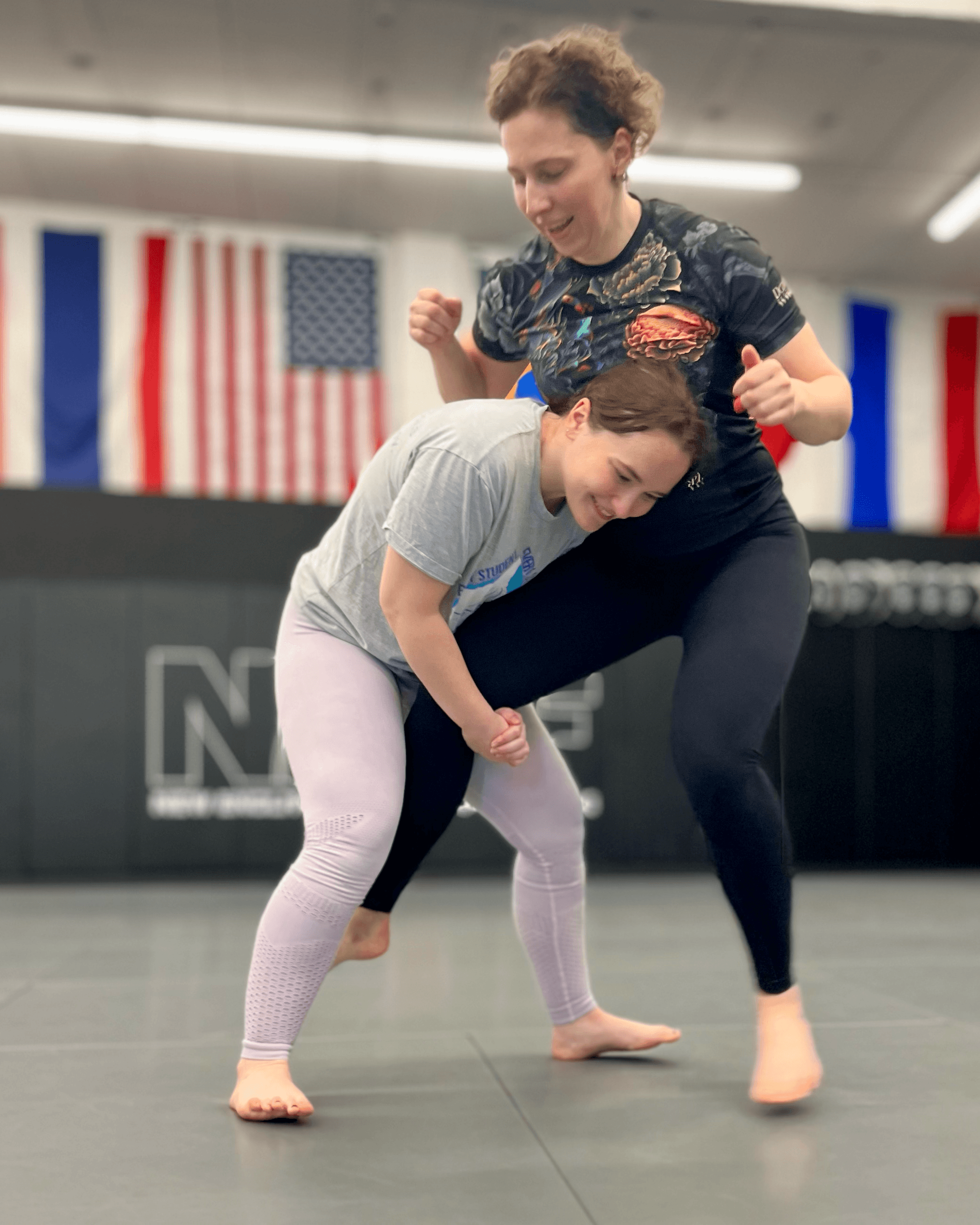 Two women practicing wrestling technique.